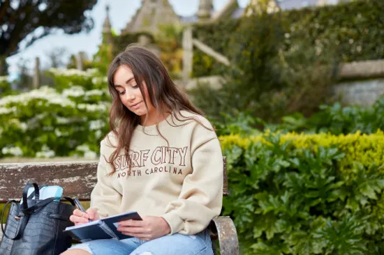 Female Student in front of Abbey working in a notebook