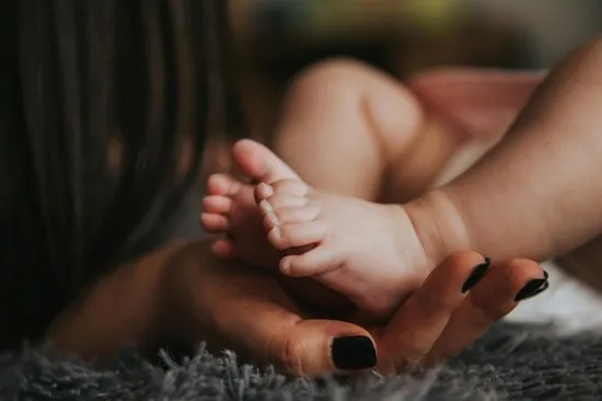 A woman's hands holding a baby's feet